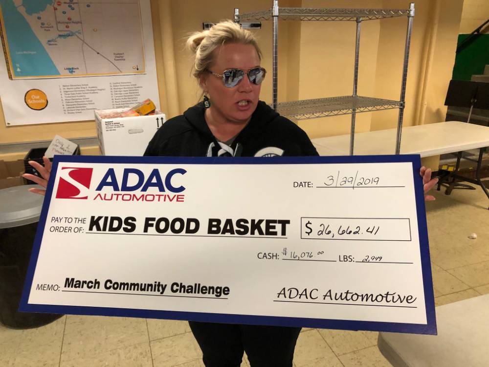 Volunteer holding a check for Kids' Food Basket